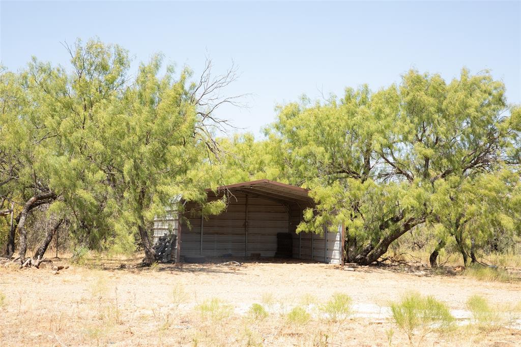 1789 Taack Road Olney, TX 76374 - Photo 18 of 18 Metal-sided shelter with a sloped roof amidst mature trees