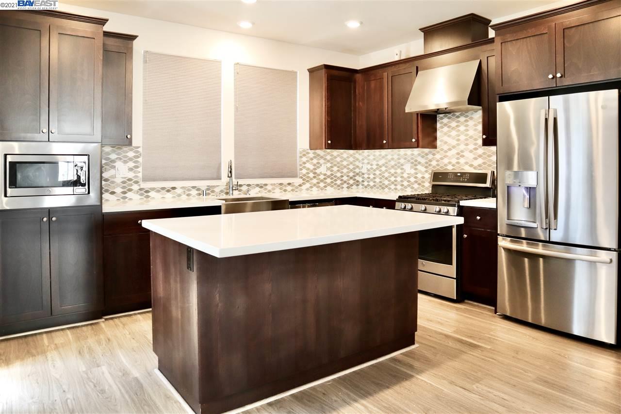 a kitchen with stainless steel appliances a sink a stove a refrigerator and cabinets