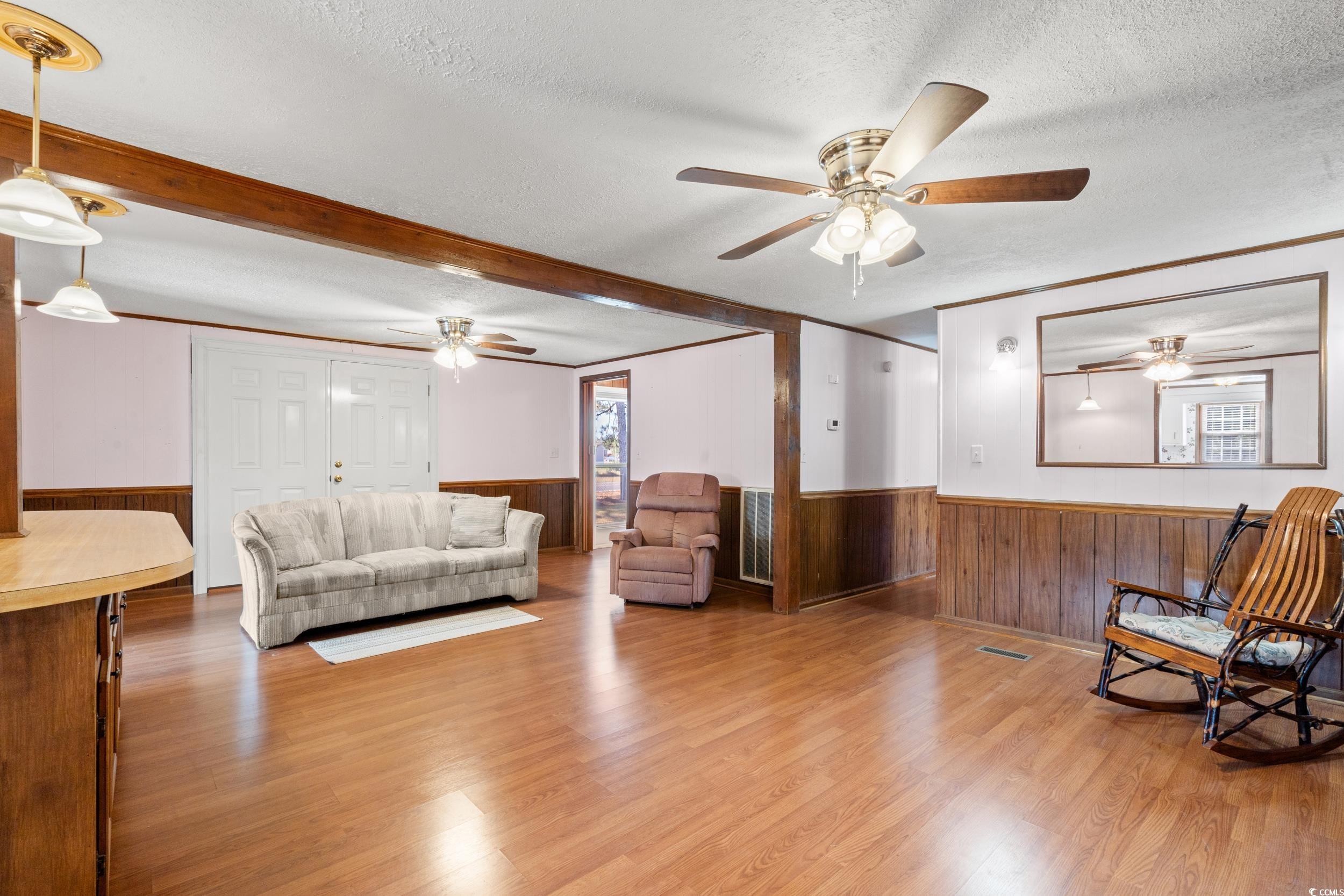4422 Grady Road Mullins, SC 29574 - Photo 5 of 28 Living area featuring a textured ceiling, light wood-style floors, healthy amount of natural light, a wainscoted wall, and wooden walls
