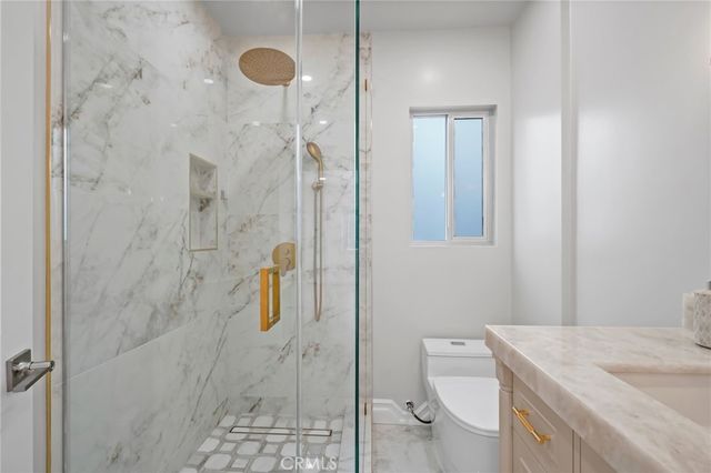 a bathroom with a granite countertop shower a sink and toilet