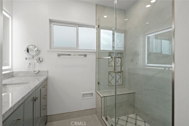 a bathroom with a granite countertop shower a sink and mirror