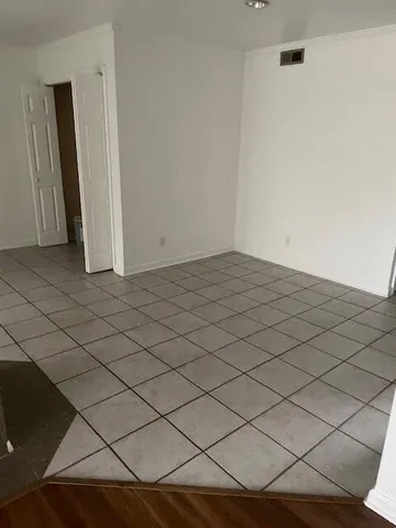 an empty room with wooden floor fire place and a window