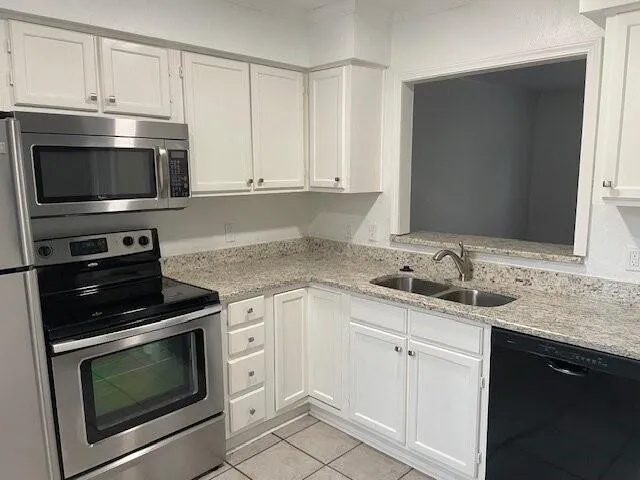 a kitchen with granite countertop white cabinets and stainless steel appliances