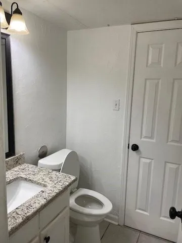 a bathroom with a granite countertop sink toilet and a mirror