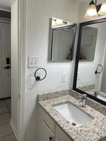 a bathroom with a granite countertop sink and a mirror
