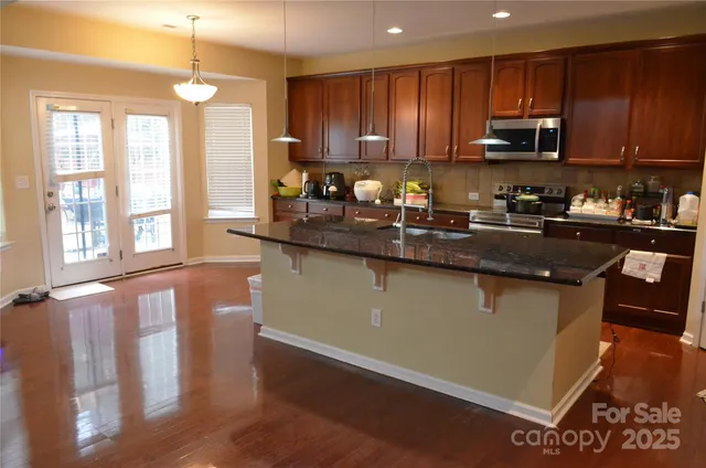a kitchen with granite countertop a stove top oven a sink a counter space and cabinets