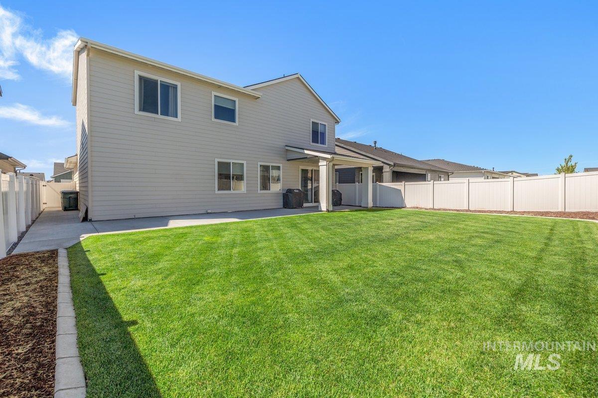 1380 West Chilitna Street Meridian, ID 83642 - Photo 44 of 50 Expansive backyard featuring a manicured lawn, full white privacy fencing, and a covered patio area