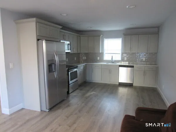a kitchen with stainless steel appliances granite countertop a refrigerator a sink a stove and white cabinets