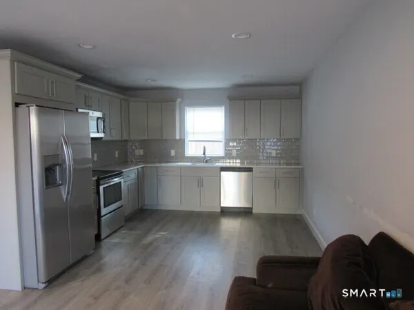 a kitchen with granite countertop a refrigerator and wooden floors