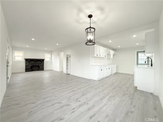 a view of empty room with wooden floor and kitchen view