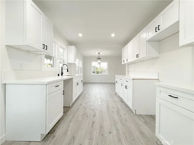 a kitchen with cabinets wooden floor and stainless steel appliances