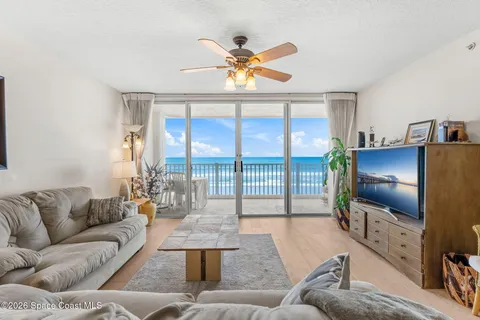 a living room with furniture a floor to ceiling window and a flat screen tv
