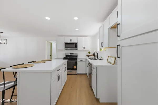 a kitchen with a sink a stove top oven a refrigerator and white cabinets