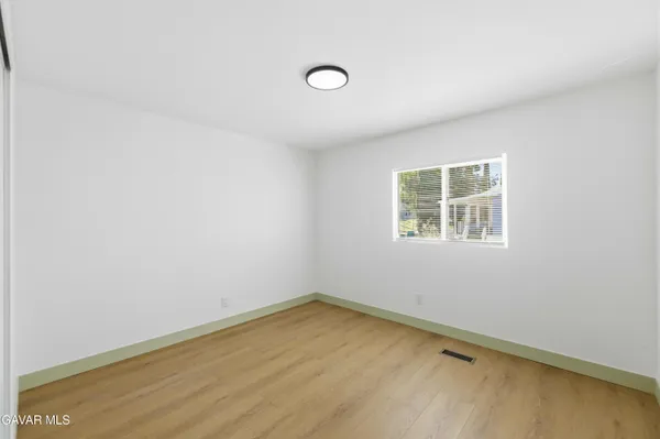 a view of an empty room with wooden floor and fan