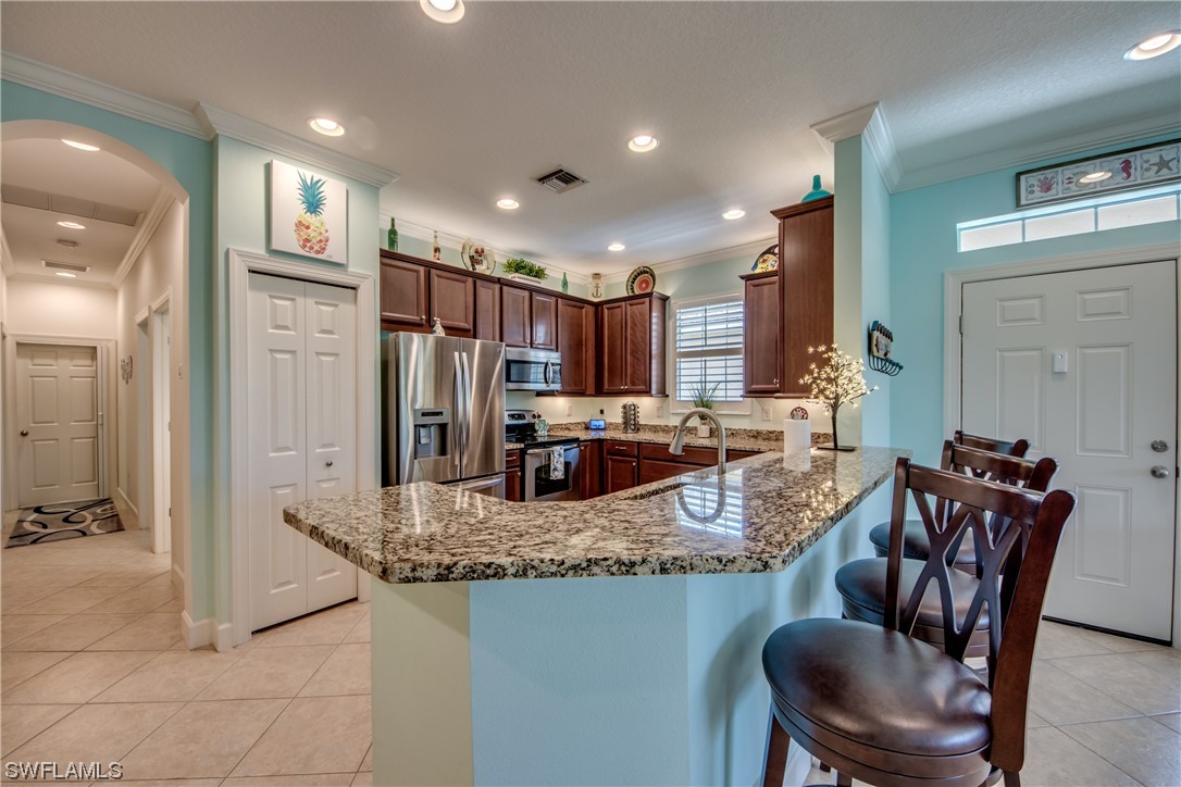 10420 Peso Del Rio Drive Fort Myers, FL 33908 - Photo 13 of 50 a kitchen with granite countertop kitchen island stainless steel appliances a refrigerator a stove a dining table and chairs