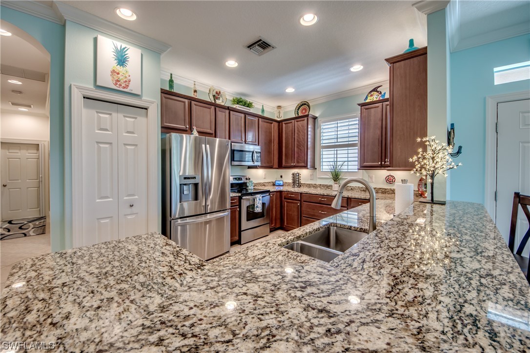 10420 Peso Del Rio Drive Fort Myers, FL 33908 - Photo 14 of 50 a kitchen with stainless steel appliances granite countertop a refrigerator oven stove a sink dishwasher a dining table and chairs with wooden floor
