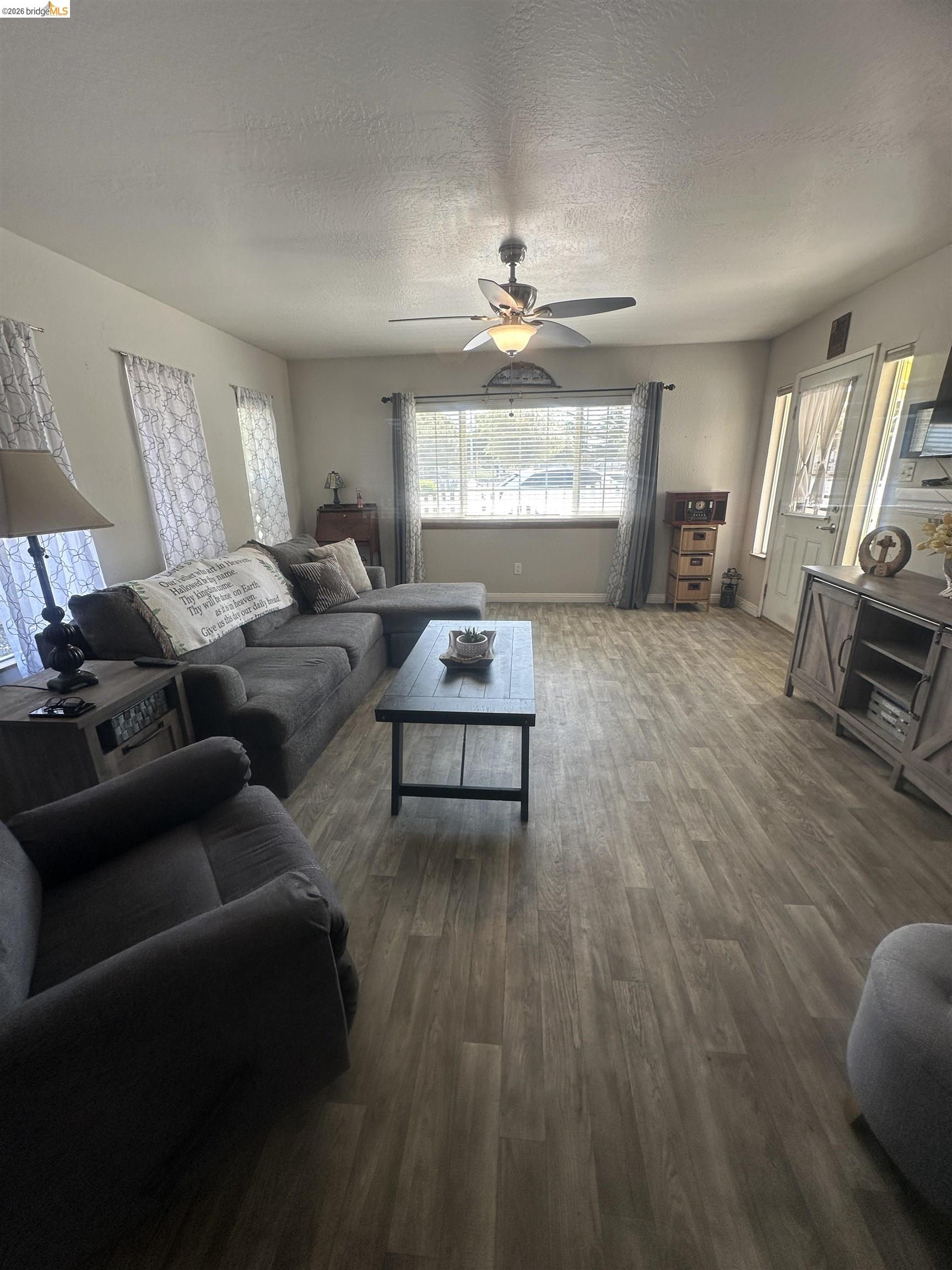 2831 Fabian Road Tracy, CA 95377 - Photo 6 of 23 Spacious living area featuring wood-finish flooring, a ceiling fan, and abundant natural light from multiple windows
