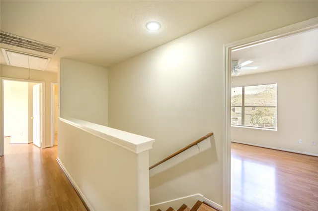 an empty room with wooden floor and a ceiling fan