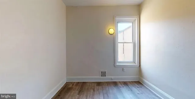 a view of empty room with window and wooden floor