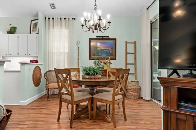 a dining room with furniture a chandelier and wooden floor