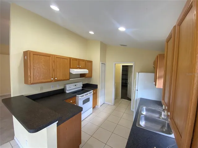 a kitchen with stainless steel appliances granite countertop a sink a stove and a refrigerator