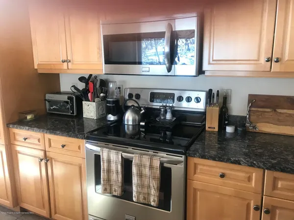 a kitchen with granite countertop a sink a stove and cabinets