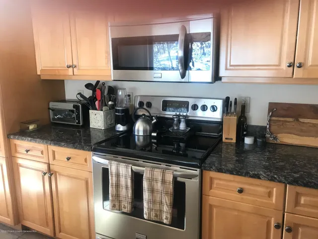 a kitchen with granite countertop a sink a stove and cabinets