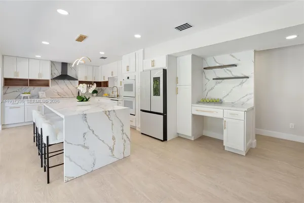 a large white kitchen with stainless steel appliances lots of white cabinets