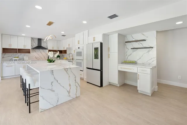 a large white kitchen with stainless steel appliances lots of white cabinets