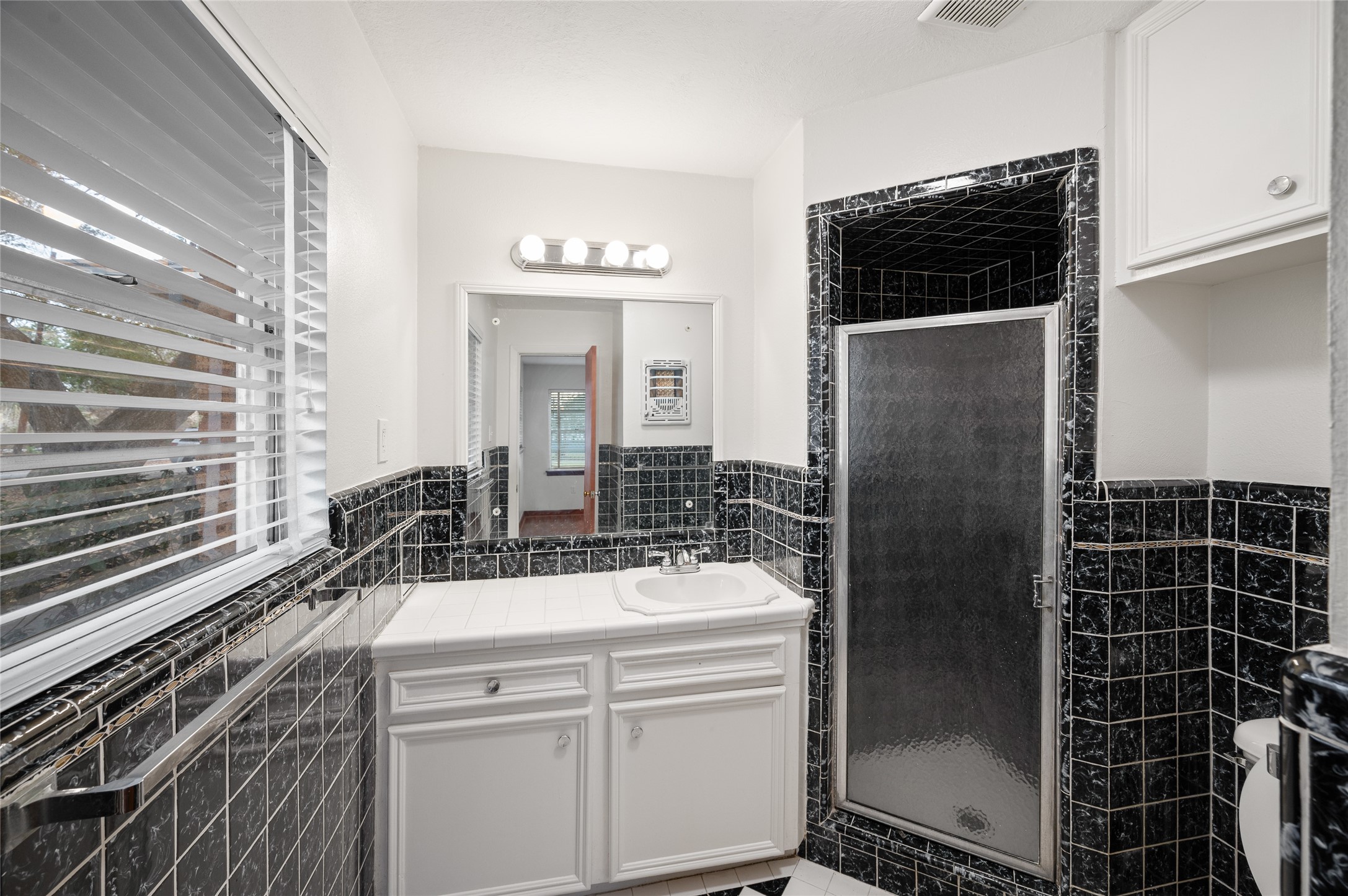 405 Hohldale Street Houston, TX 77091 - Photo 11 of 39 Primary bathroom featuring black marble tile, walk-in shower, and natural light.