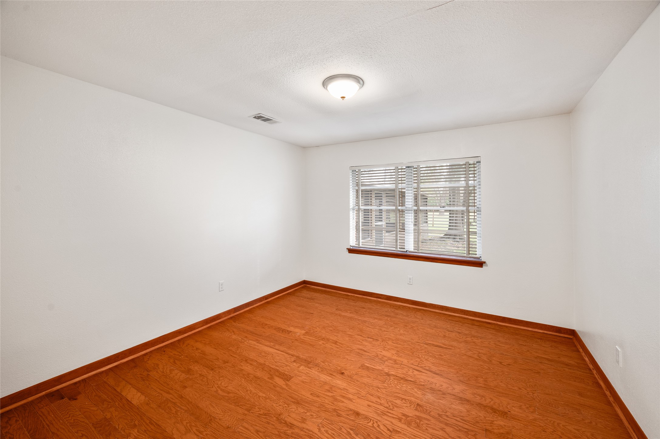 405 Hohldale Street Houston, TX 77091 - Photo 17 of 39 Secondary bedroom with warm wood flooring, ample natural light from a large window, and a crisp, clean design perfect for creating your dream space.