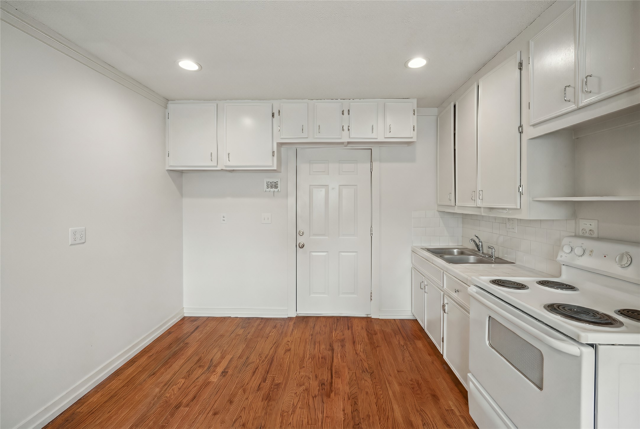 405 Hohldale Street Houston, TX 77091 - Photo 27 of 39 The cabin kitchen and dining area features sleek white cabinetry and warm wood floors, offering a cozy and inviting space for culinary creativity and shared meals.