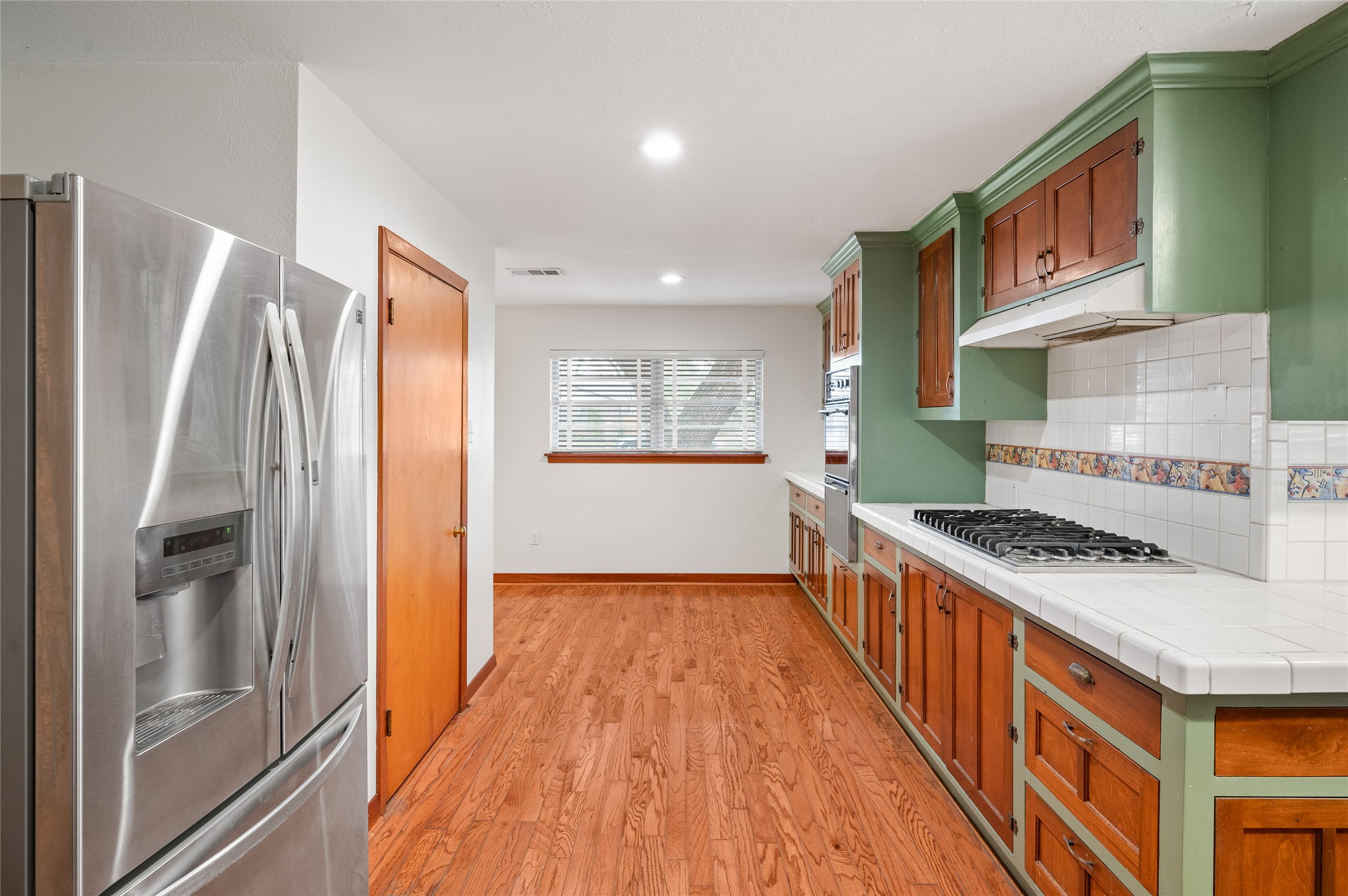 405 Hohldale Street Houston, TX 77091 - Photo 8 of 39 Additional kitchen view showing stainless refrigerator, generous counter space, and clear sightlines into adjacent living areas.