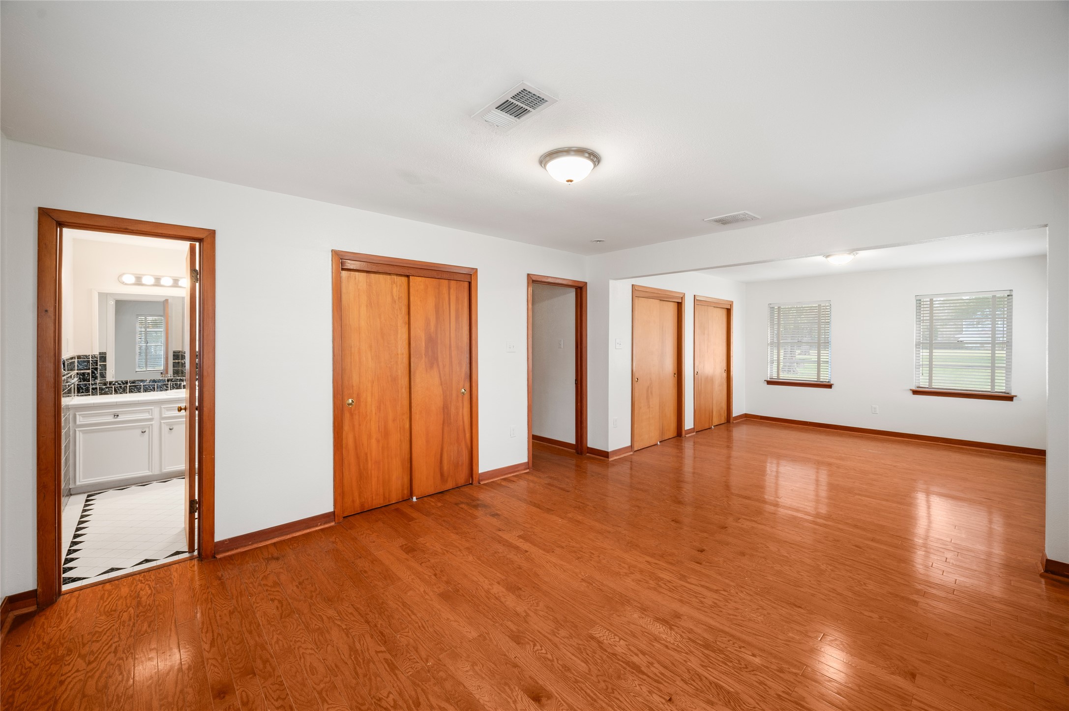 405 Hohldale Street Houston, TX 77091 - Photo 9 of 39 Primary bedroom with hardwood floors, abundant natural light from multiple windows, three closets, and ensuite access.