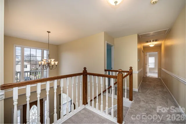a view of staircase with railing and a chandelier