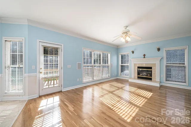 a view of an empty room with wooden floor fireplace and a window