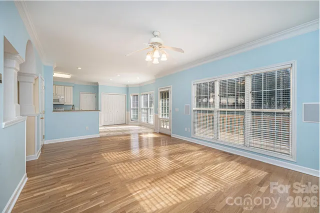 a view of empty room with wooden floor and fan