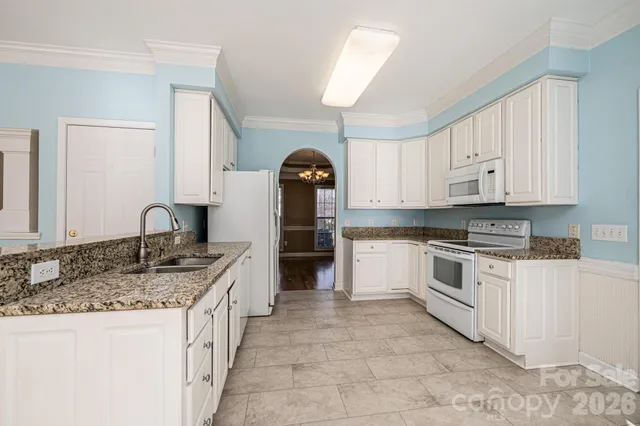 a kitchen with granite countertop a stove top oven sink and cabinets