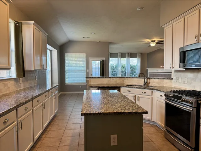 a large kitchen with granite countertop a stove and a sink
