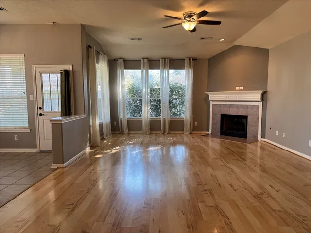 an empty room with wooden floor fireplace and windows