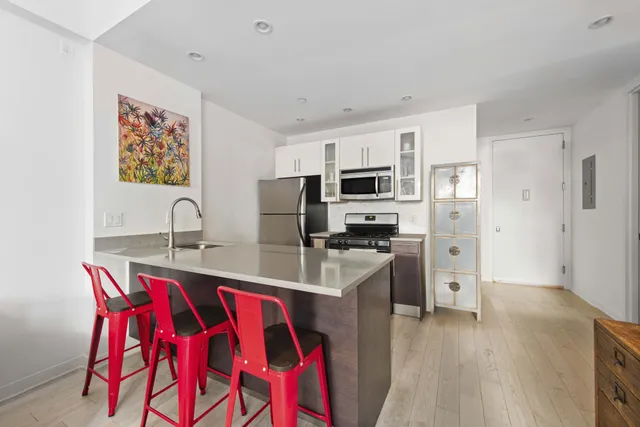 a kitchen with stainless steel appliances kitchen island granite countertop a refrigerator a stove a microwave oven a sink with island and chairs