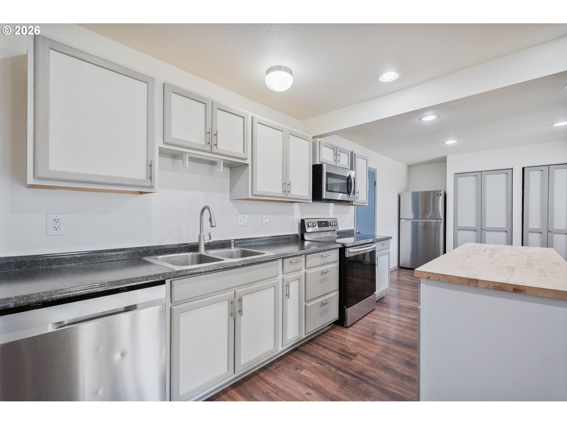 4703 Merlin Street Longview, WA 98632 - Photo 10 of 25 a kitchen with stainless steel appliances granite countertop a sink dishwasher stove and white cabinets with wooden floor