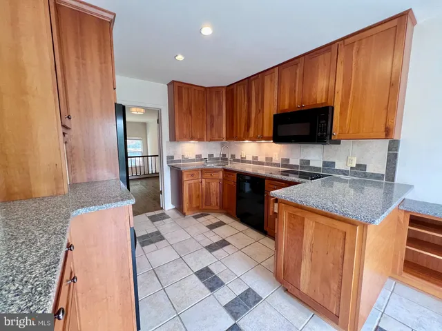 a kitchen with stainless steel appliances granite countertop a stove top oven a sink dishwasher and a refrigerator with wooden floor