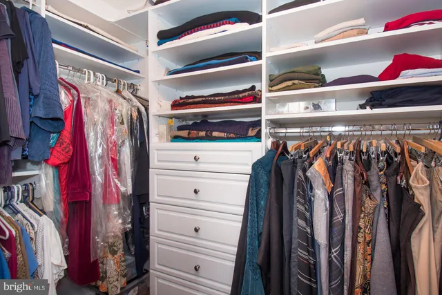a view of walk in closet with clothes and shoes