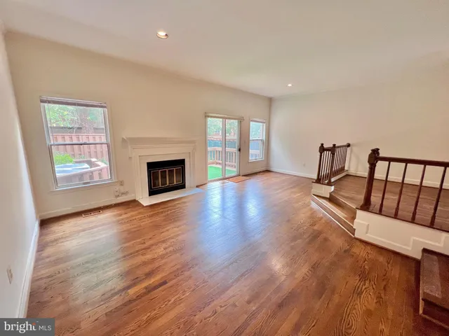 an empty room with fireplace wooden floor and windows