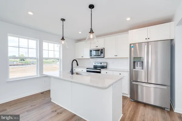 a kitchen with stainless steel appliances granite countertop a refrigerator a sink dishwasher a kitchen island with wooden floor and cabinets