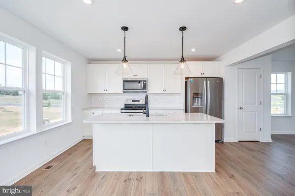 a kitchen with stainless steel appliances kitchen island wooden floors and white cabinets