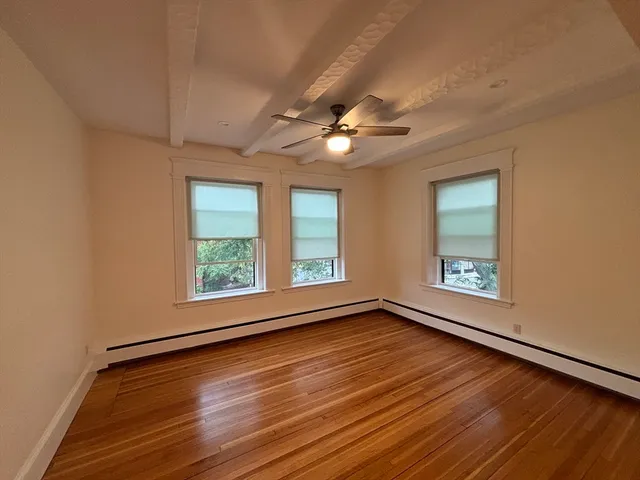 a view of an empty room with a window and wooden floor