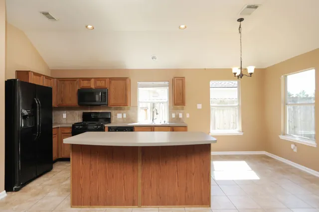 a kitchen with kitchen island granite countertop a stove a refrigerator a sink dishwasher with a dining table and chairs