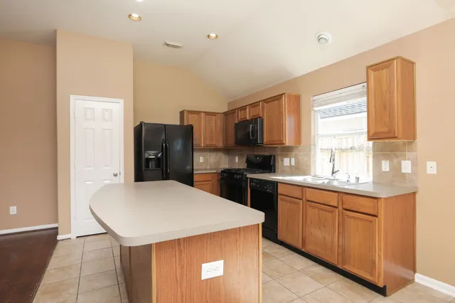 a kitchen with a sink a stove a refrigerator a center island and cabinets
